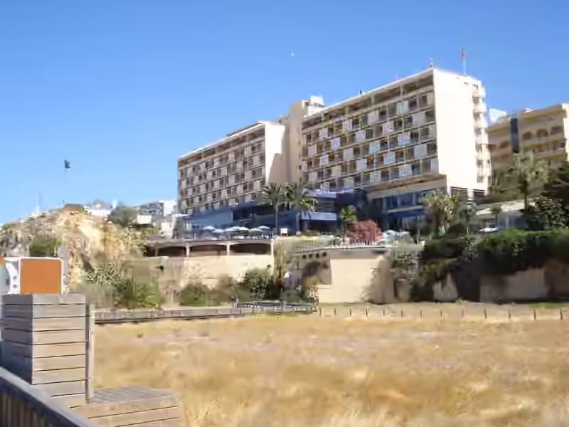Hotel Algarve Casino seen from the sand of Praia da Rocha, with its balconied wings and the pool terrace above the cliff