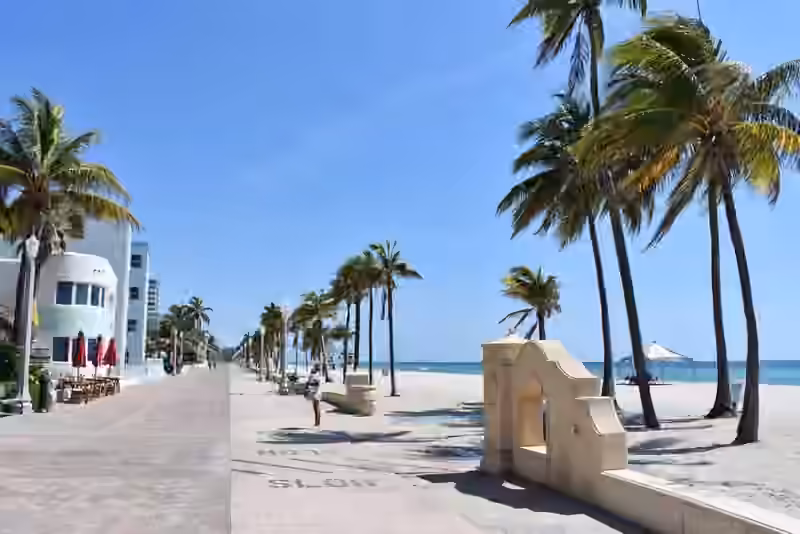 The Hollywood Beach Broadwalk in Florida: a wide paved promenade lined with palm trees beside the sand and the ocean