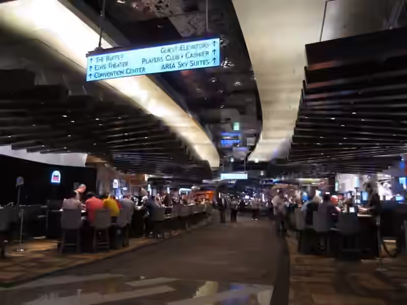 A walkway through the casino floor at ARIA in 2010, with an overhead sign pointing to the guest elevators, the convention center and ARIA Sky Suites