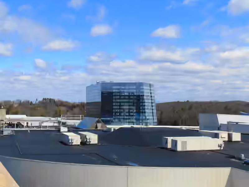 The glass Earth Tower of Mohegan Sun seen across the roofs of the resort, with wooded hills behind