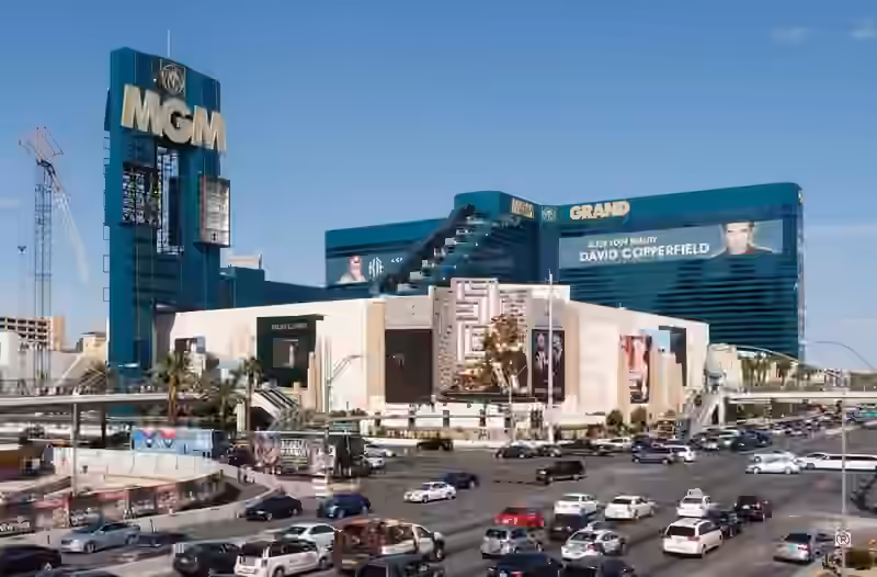 MGM Grand seen in daylight across the junction of Las Vegas Boulevard and Tropicana Avenue in 2013, the green glass hotel towers behind the entrance building and its bronze lion