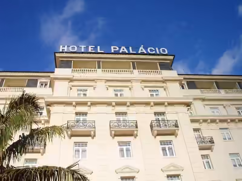 Upper floors of the Hotel Palácio facade in Estoril, with balconies and the rooftop sign