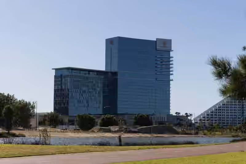 Crown Towers Perth seen across a lake in Burswood Park, with the white terraced wing of a neighbouring hotel on the right