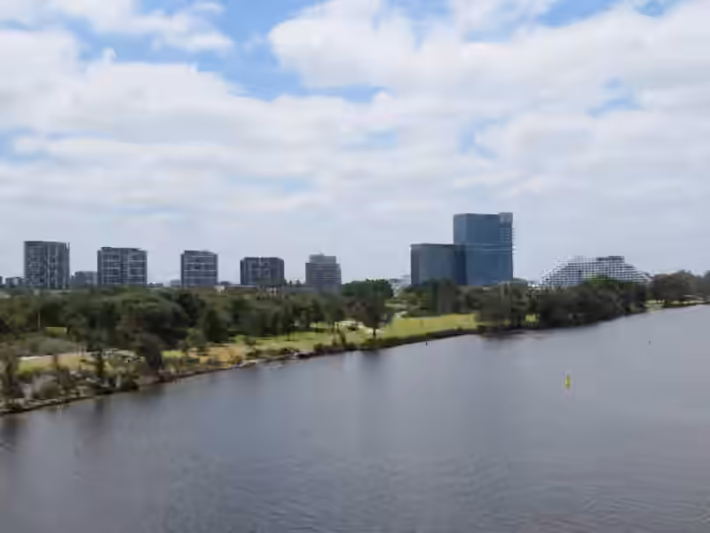 Crown Perth seen across the Swan River, with riverside parkland in front of the hotel buildings
