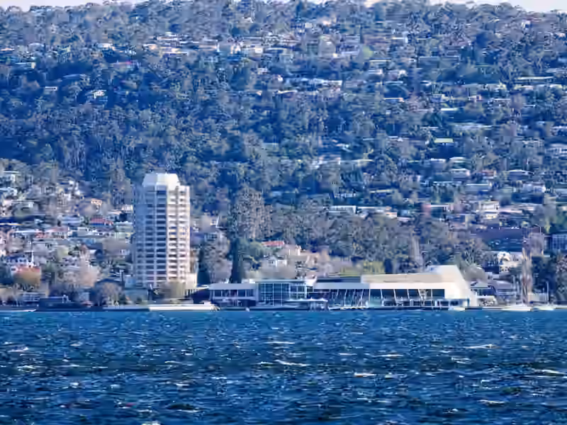 Wrest Point seen across the River Derwent, with its pale tower and low waterfront buildings below the wooded hillside of Sandy Bay