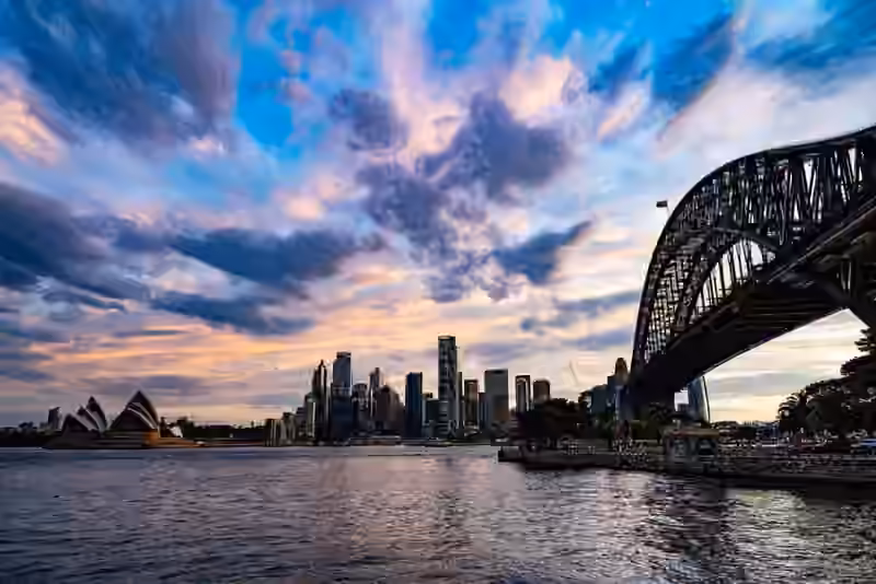 Sydney Harbour at dusk with the Opera House on the left, the city skyline in the middle and the arch of the Harbour Bridge on the right