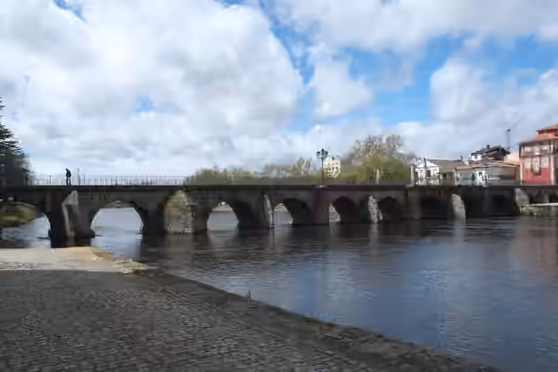 Trajan's Bridge in Chaves, a long stone bridge of low arches across the river, with houses of the town on the far bank