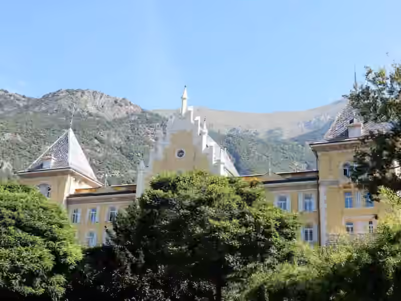 The roofline of Grand Hôtel Billia, a central stepped gable between two towers, rising above the trees of its park