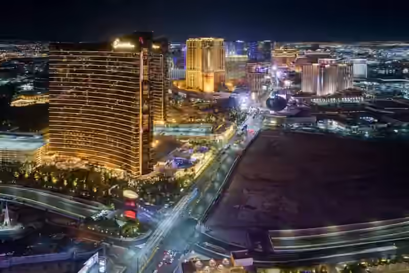 The Las Vegas Strip at night seen from a high floor, with lit hotel towers on both sides of Las Vegas Boulevard and the city lights behind
