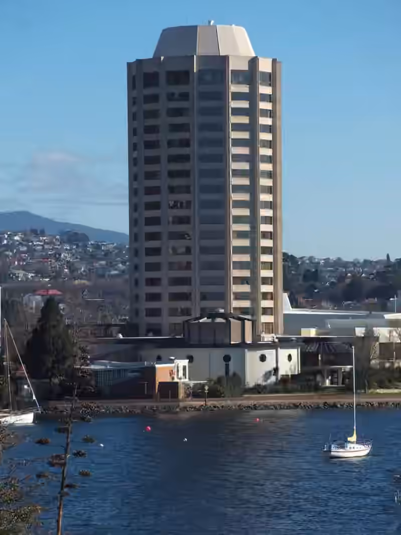 The Wrest Point hotel tower rising above the low buildings on the shore, with a sailing boat moored in front